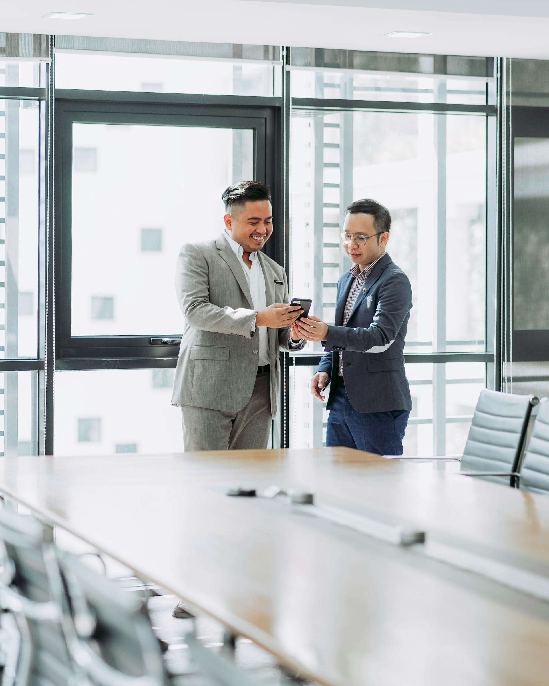 two-males-at-big-desk-looking-at-phone